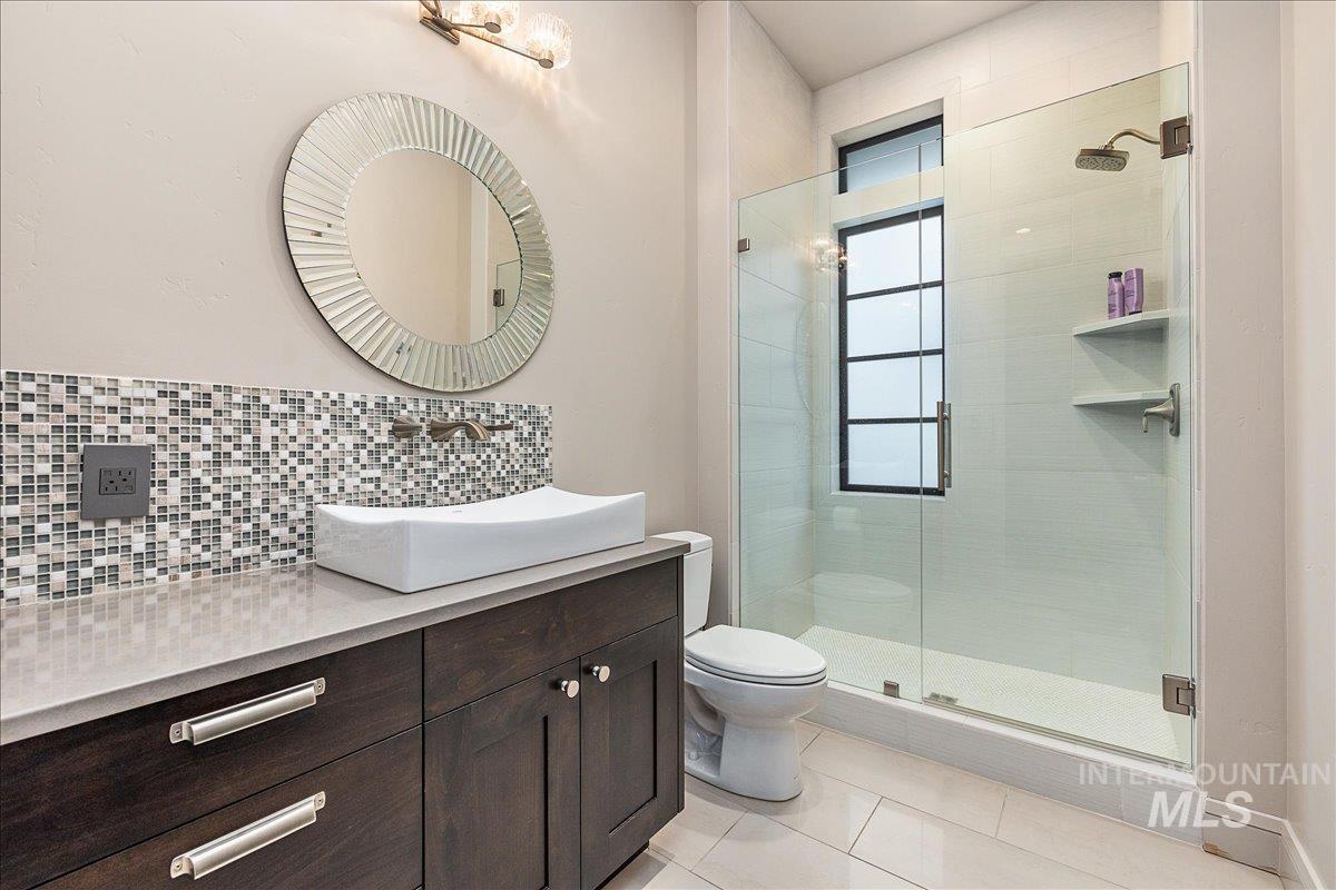 Bathroom featuring vanity, tasteful backsplash, a stall shower, and light tile patterned floors