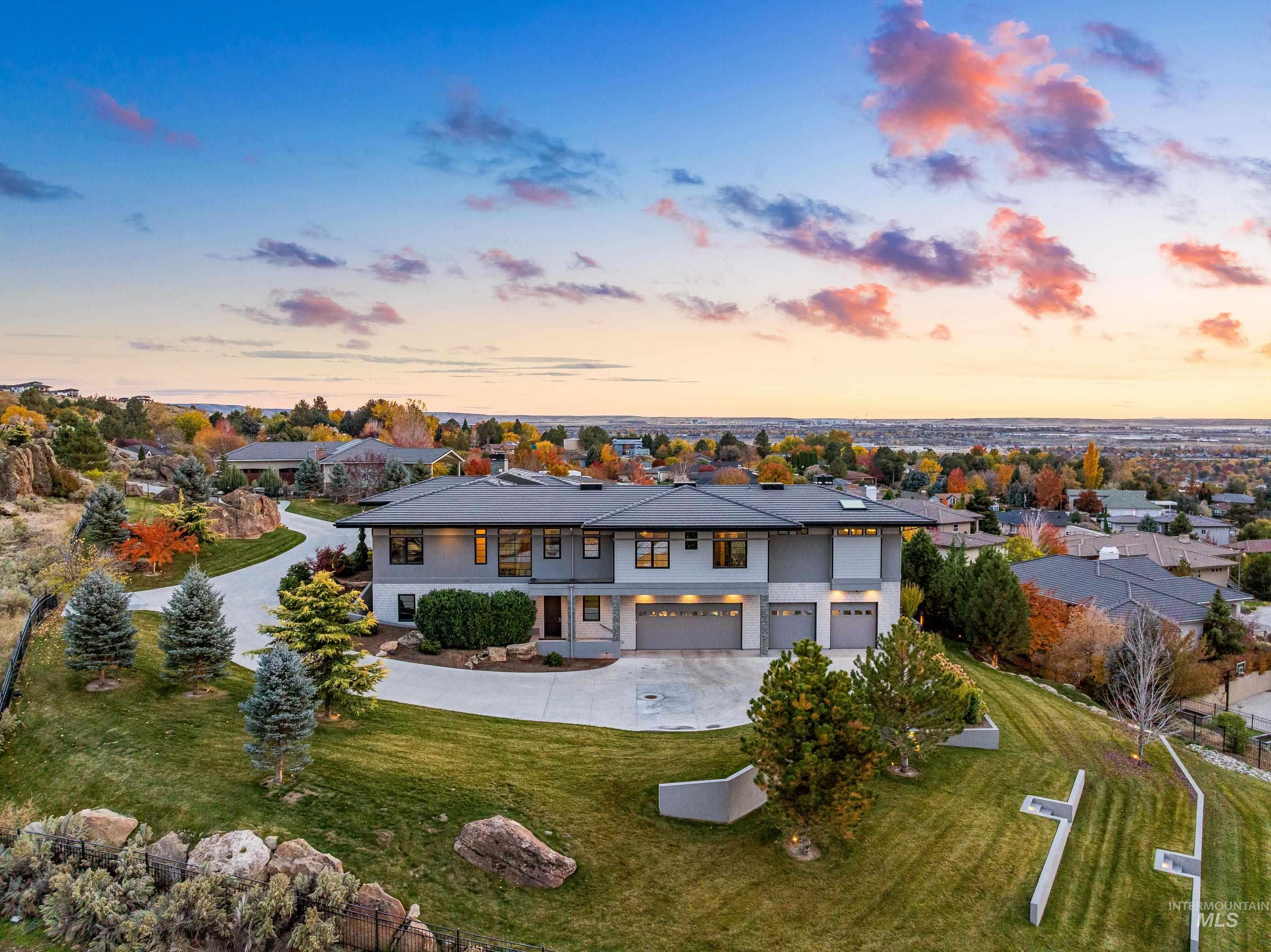 Back of property at dusk with concrete driveway, a lawn, a patio, and a garage