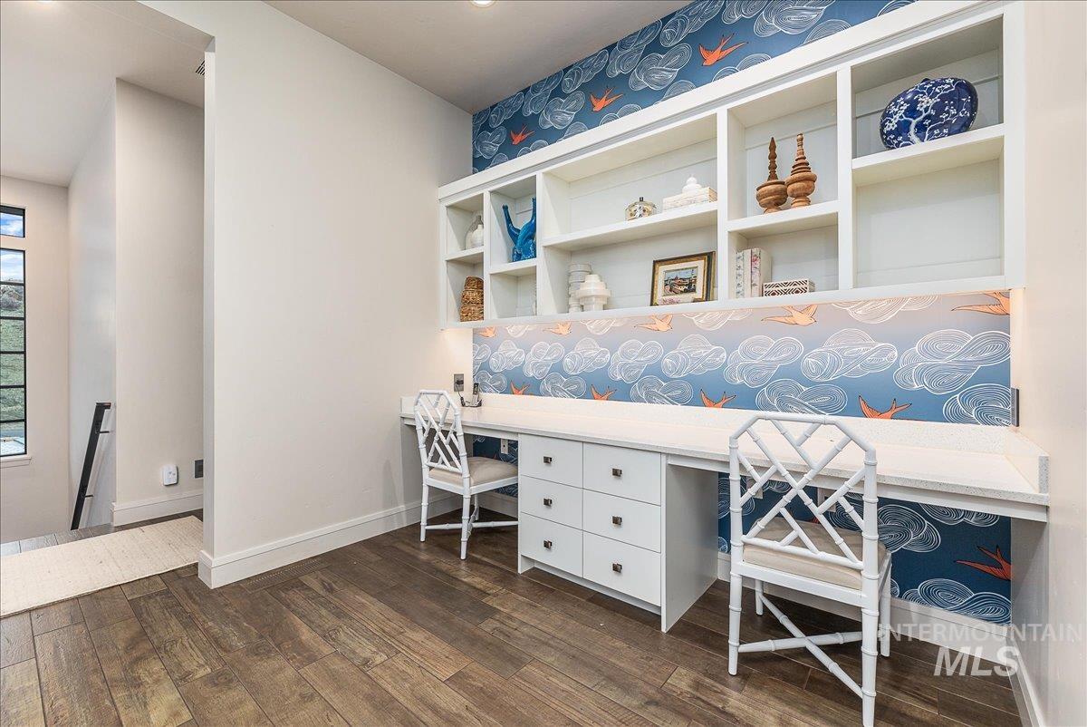 Office space with built in desk and dark wood-style flooring