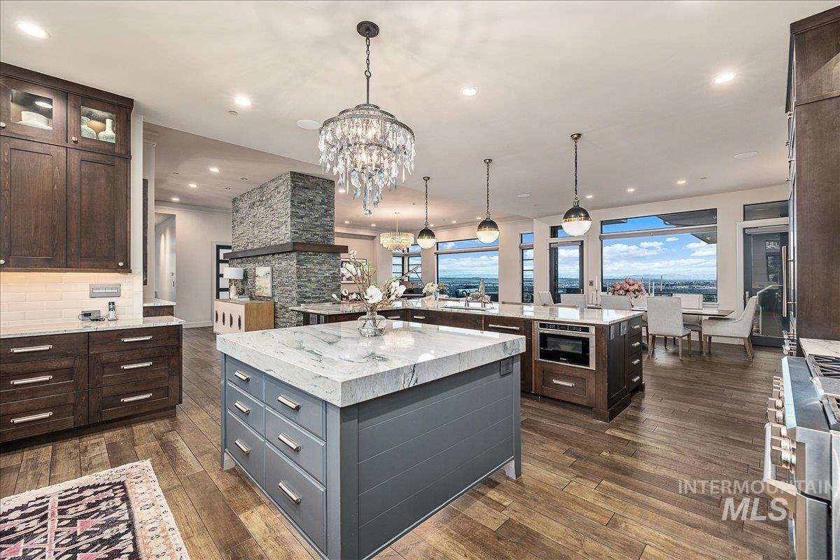 Kitchen featuring dark brown cabinets, light stone countertops, high end stainless steel range, decorative light fixtures, and recessed lighting