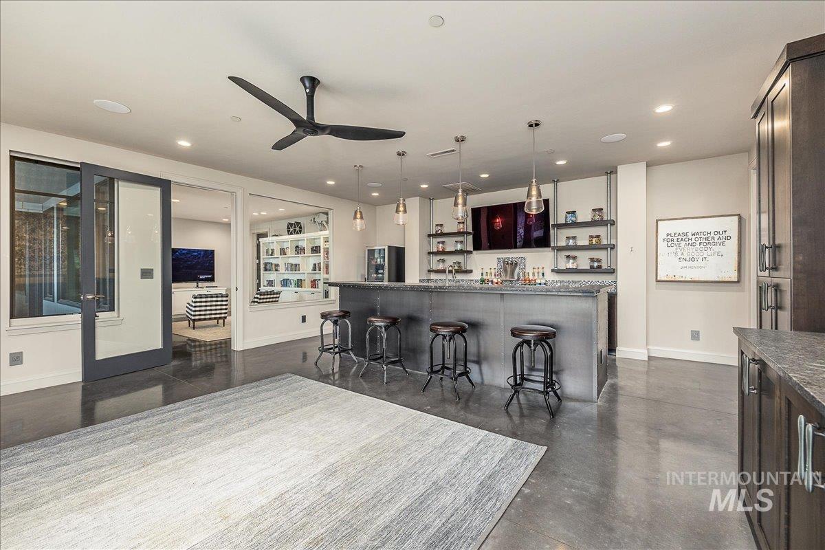 Kitchen featuring open shelves, hanging light fixtures, a breakfast bar, ceiling fan, and stainless steel fridge
