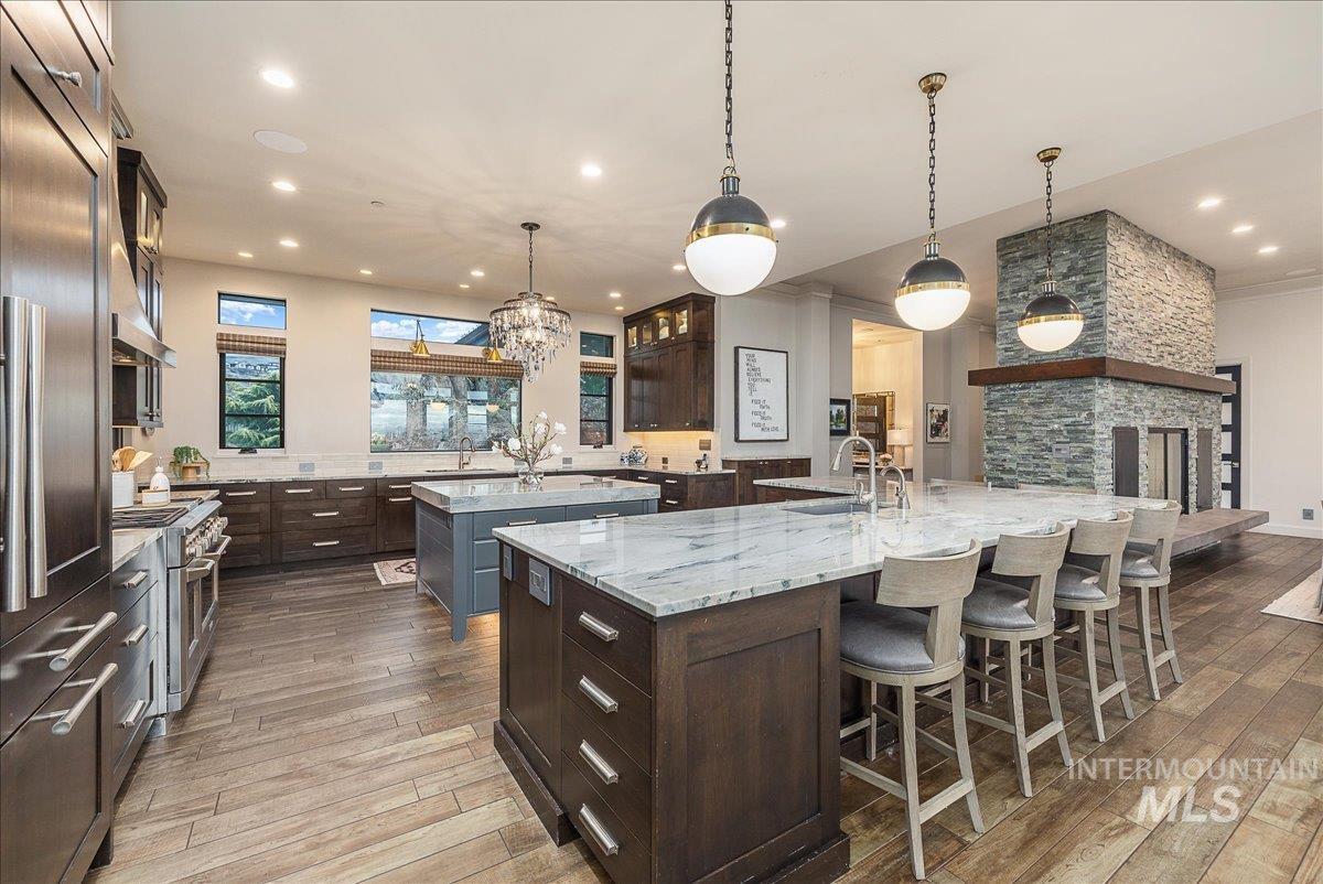 Kitchen featuring light stone countertops, hanging light fixtures, dark brown cabinets, a kitchen bar, and recessed lighting