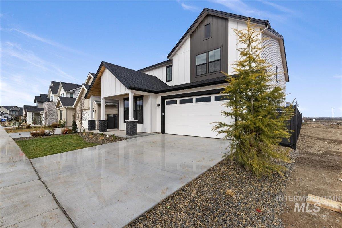 Modern farmhouse style home featuring an attached garage, board and batten siding, concrete driveway, a porch, and a residential view