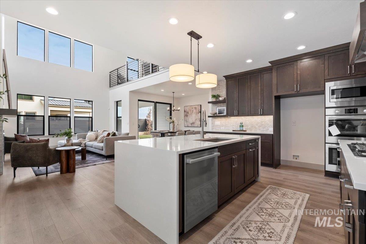 Kitchen featuring light stone countertops, pendant lighting, open floor plan, open shelves, and light wood finished floors