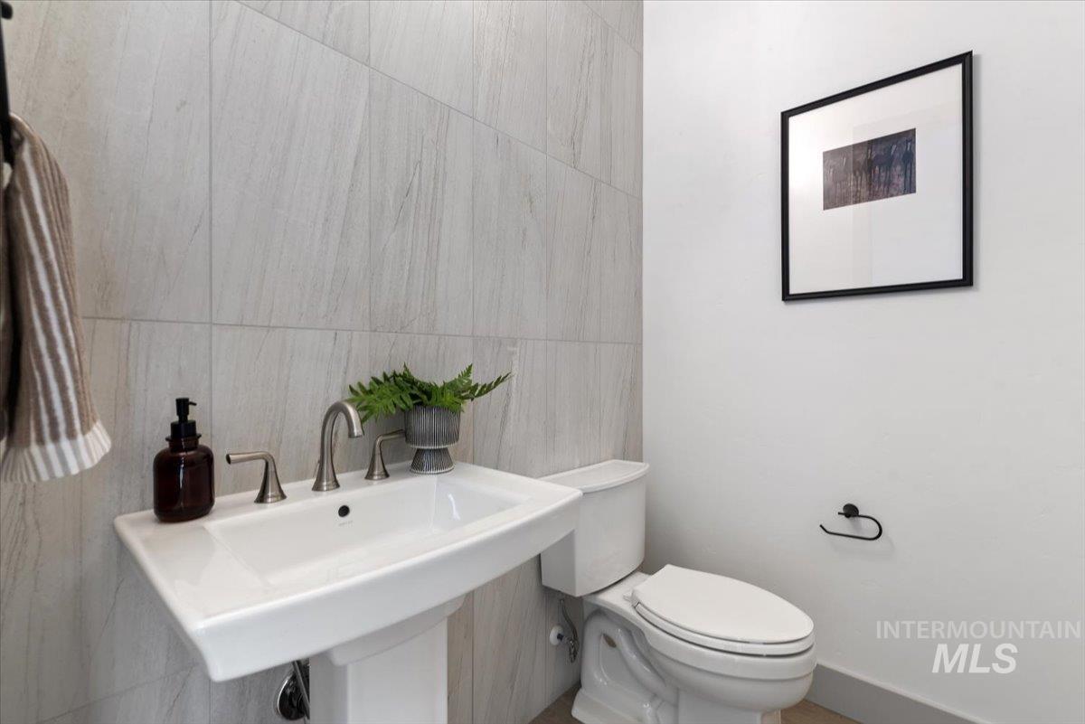Bathroom featuring tile walls and toilet