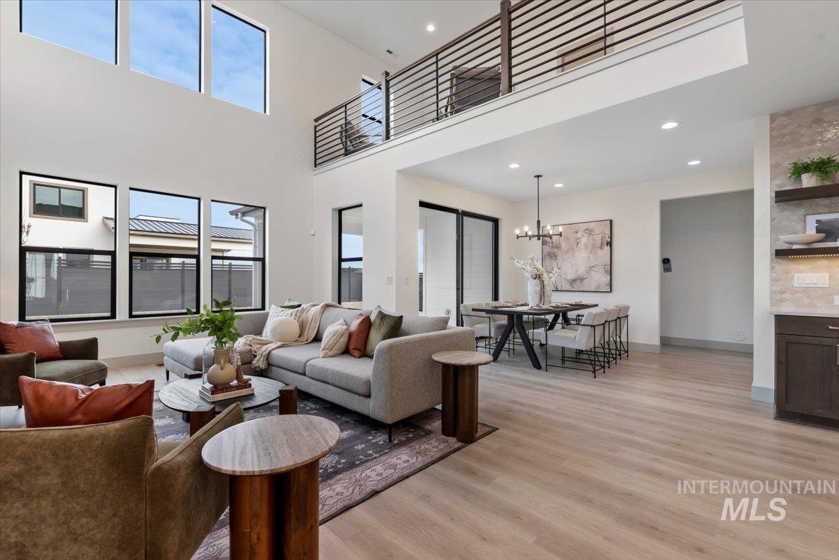 Living area featuring light wood finished floors, a high ceiling, and hanging lights