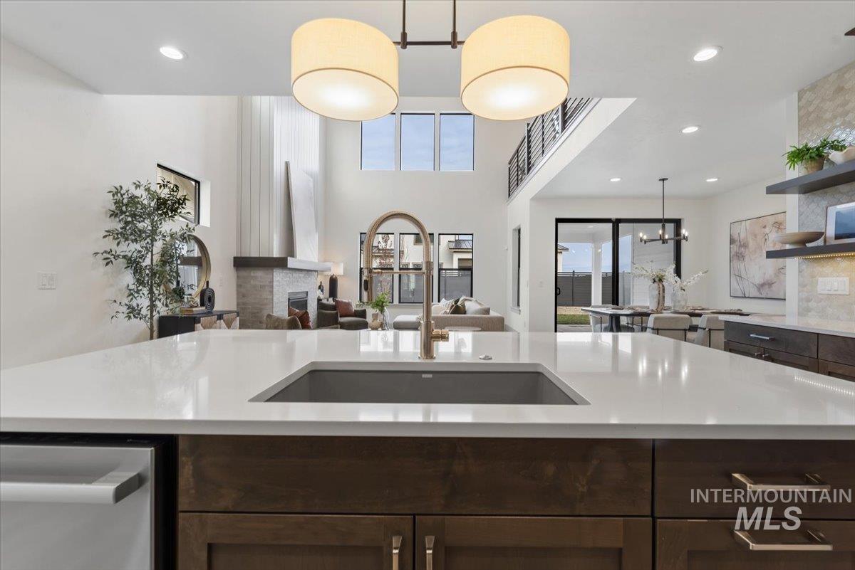 Kitchen featuring dark wood finish cabinets, open floor plan, open shelves, a fireplace, and a high ceiling