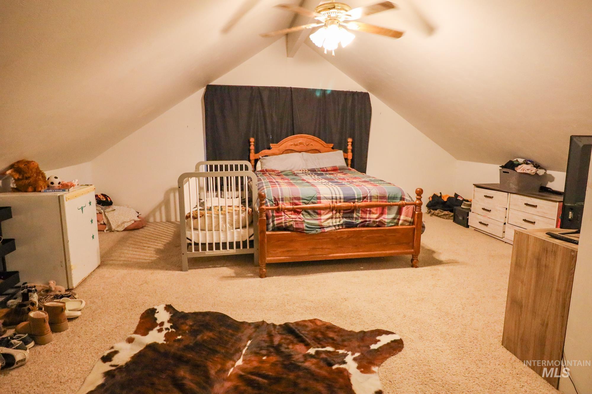 Carpeted bedroom with lofted ceiling and ceiling fan