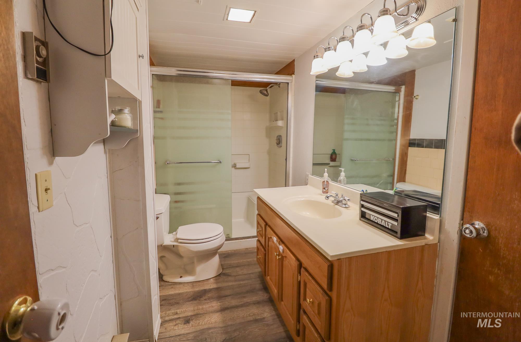 Bathroom with vanity, a stall shower, and wood finished floors