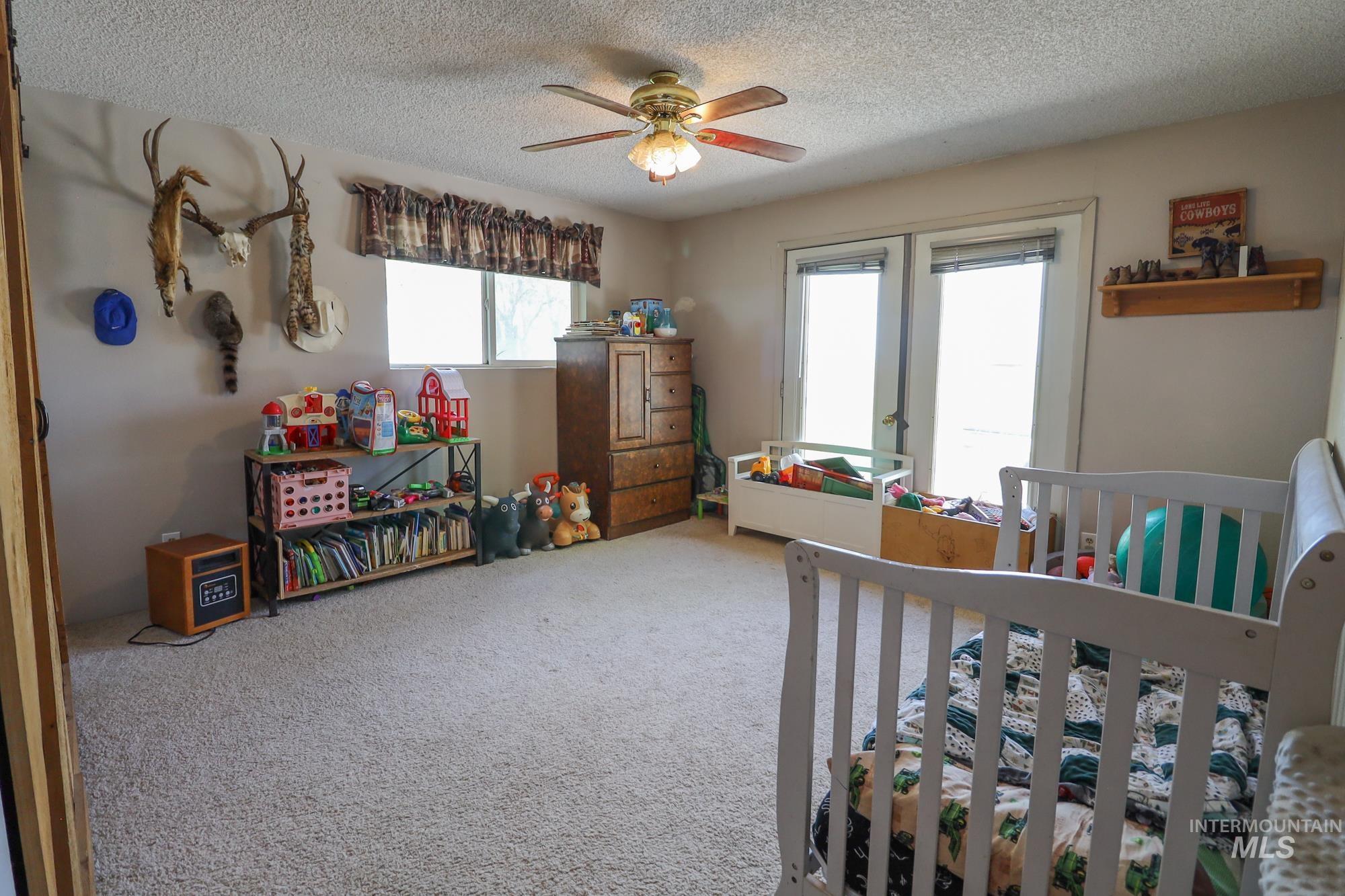Bedroom featuring french doors, a textured ceiling, carpet floors, and a ceiling fan