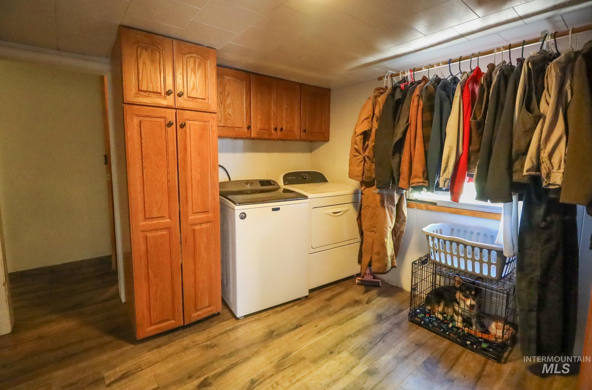 Washroom featuring washing machine and clothes dryer, light wood finished floors, and cabinet space