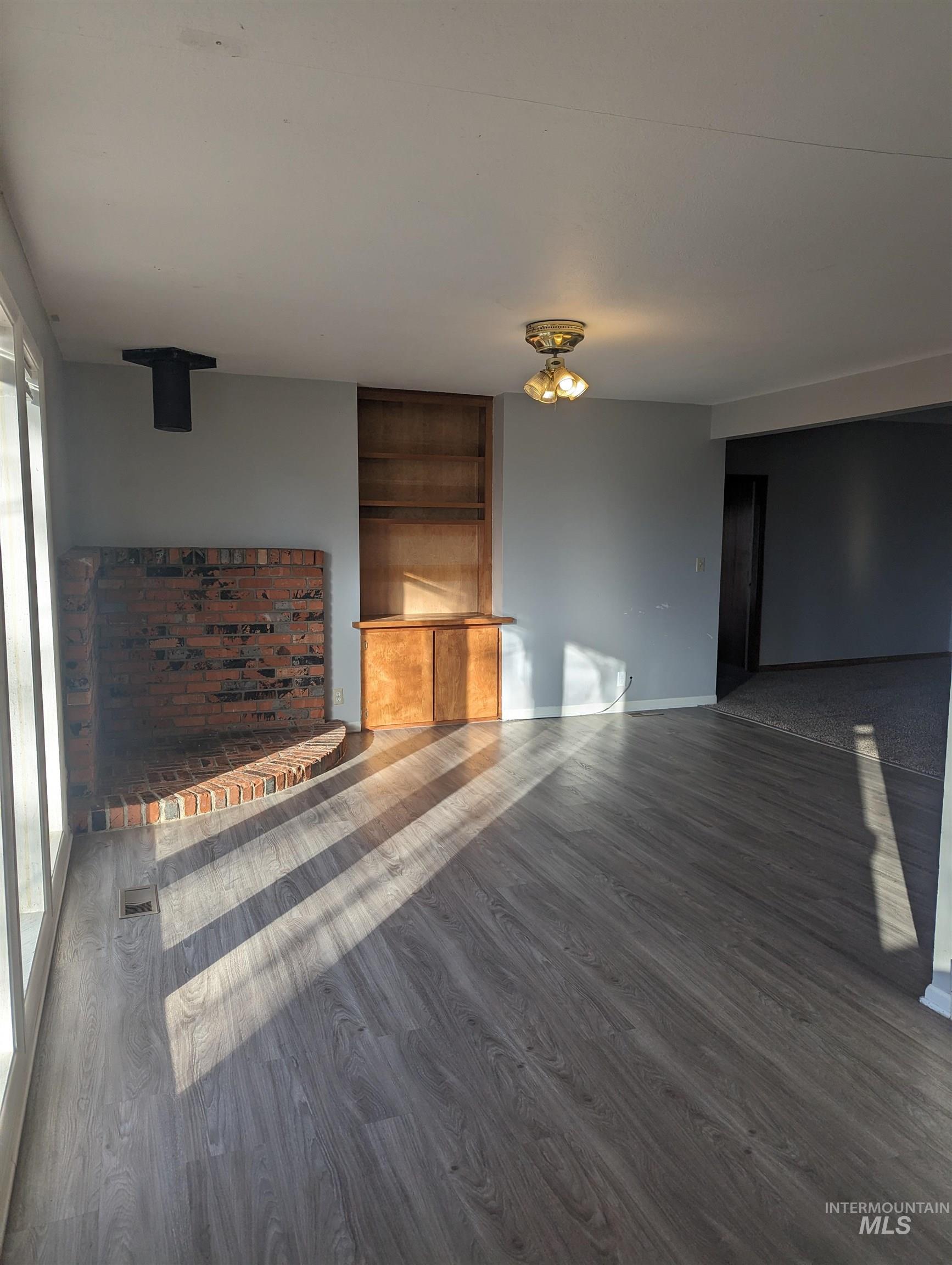 Unfurnished living room featuring dark wood-type flooring