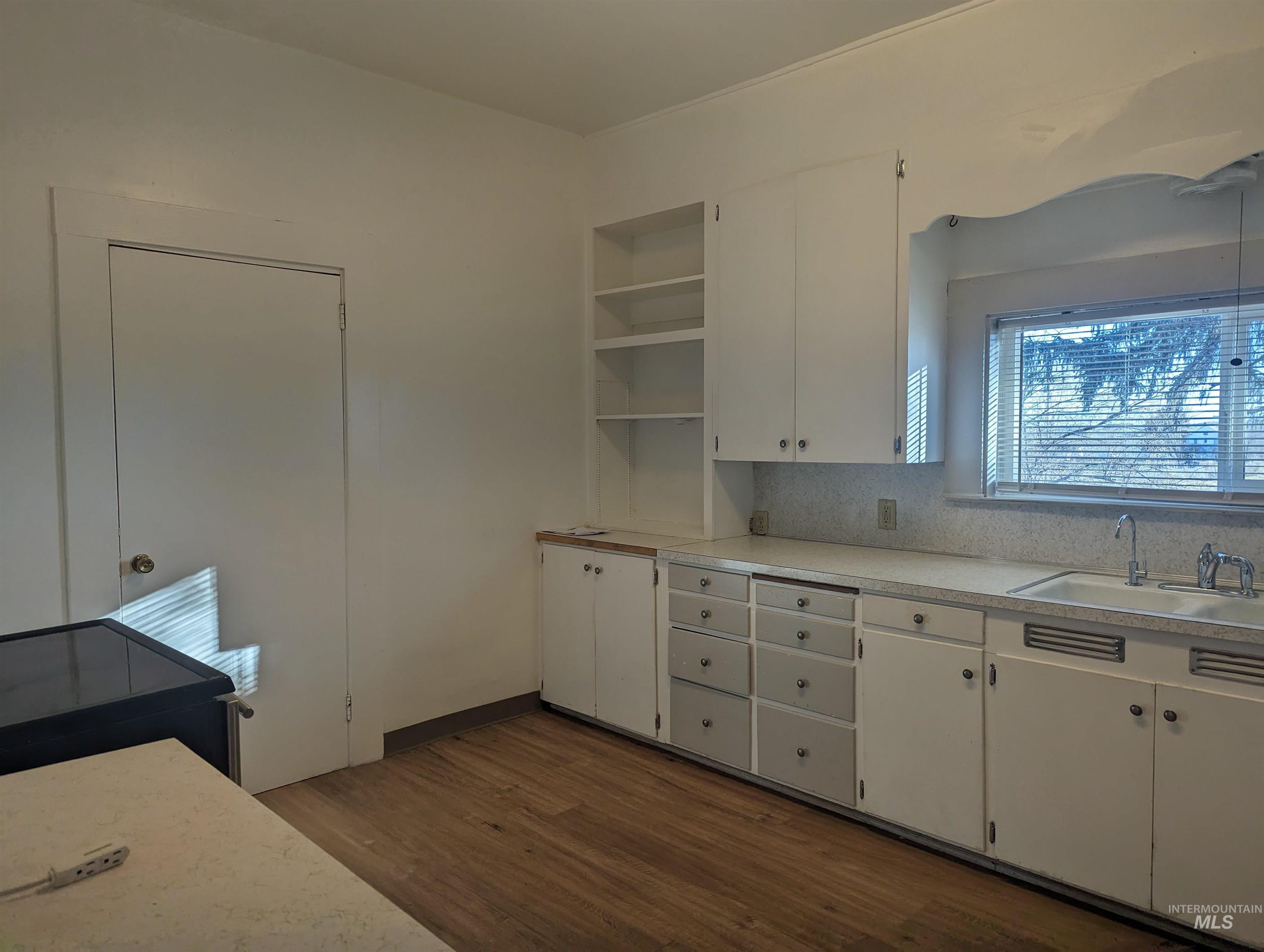 Kitchen featuring light countertops, open shelves, dark wood-style flooring, white cabinetry, and backsplash