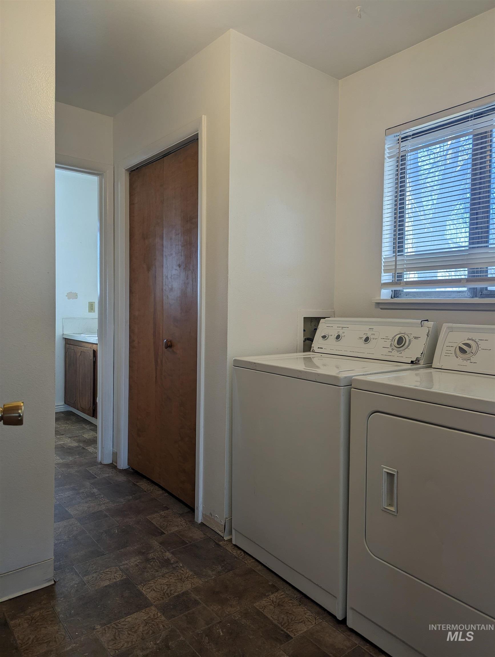 Washroom featuring washing machine and clothes dryer and dark stone finish floors