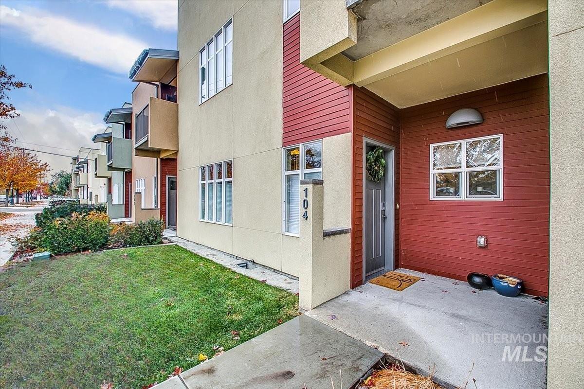View of exterior entry with stucco siding and a yard
