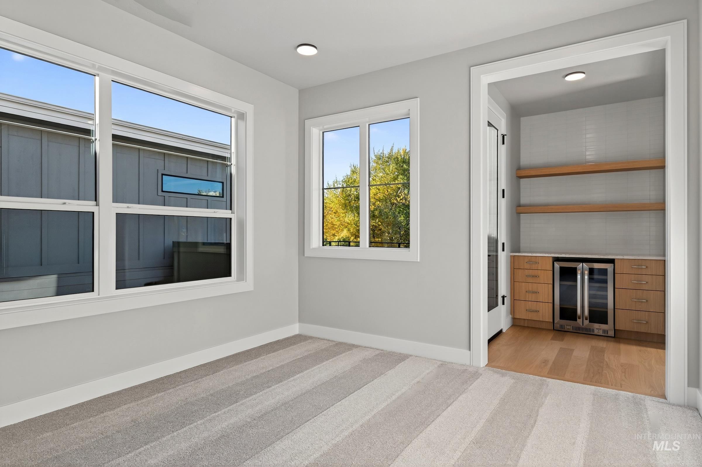 Unfurnished room featuring wine cooler and light colored carpet
