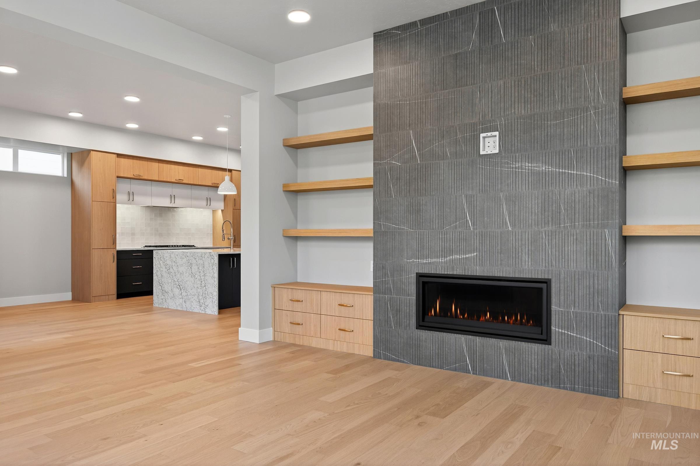 Unfurnished living room with light wood-type flooring, recessed lighting, built in shelves, and a tiled fireplace