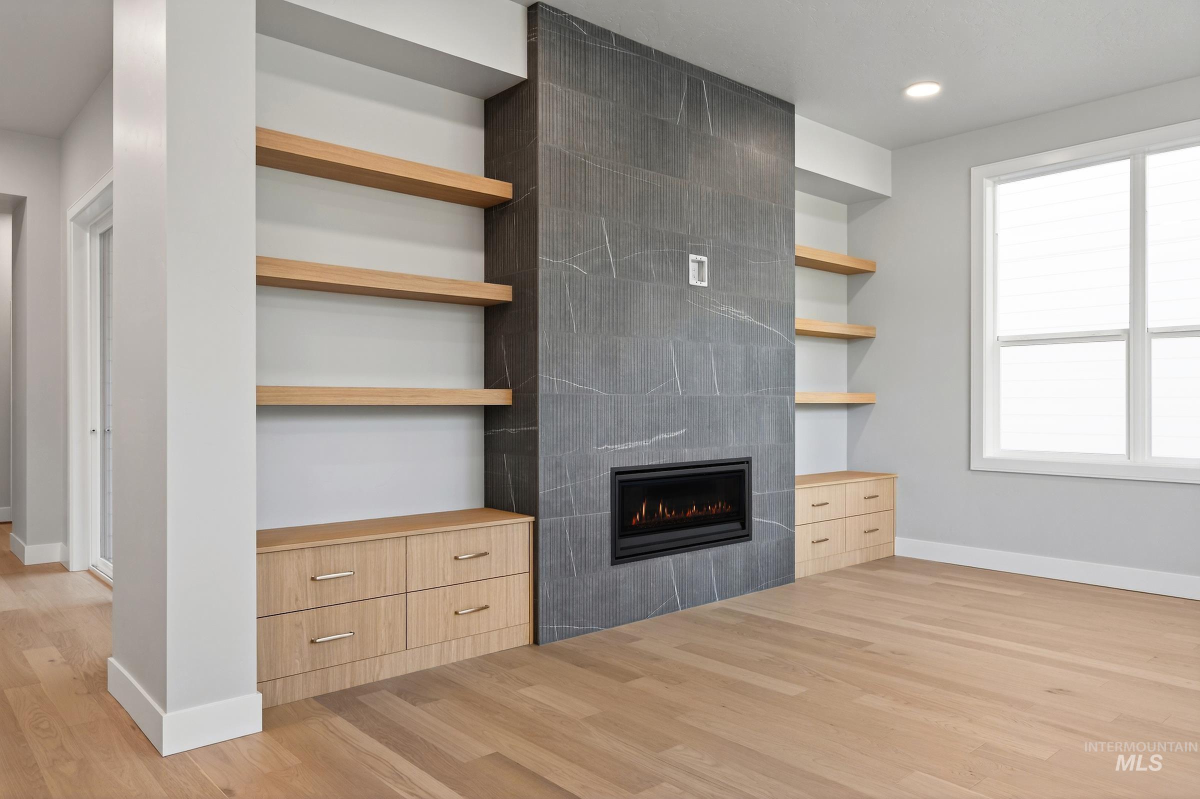 Unfurnished living room featuring a tiled fireplace, light wood-style floors, and recessed lighting