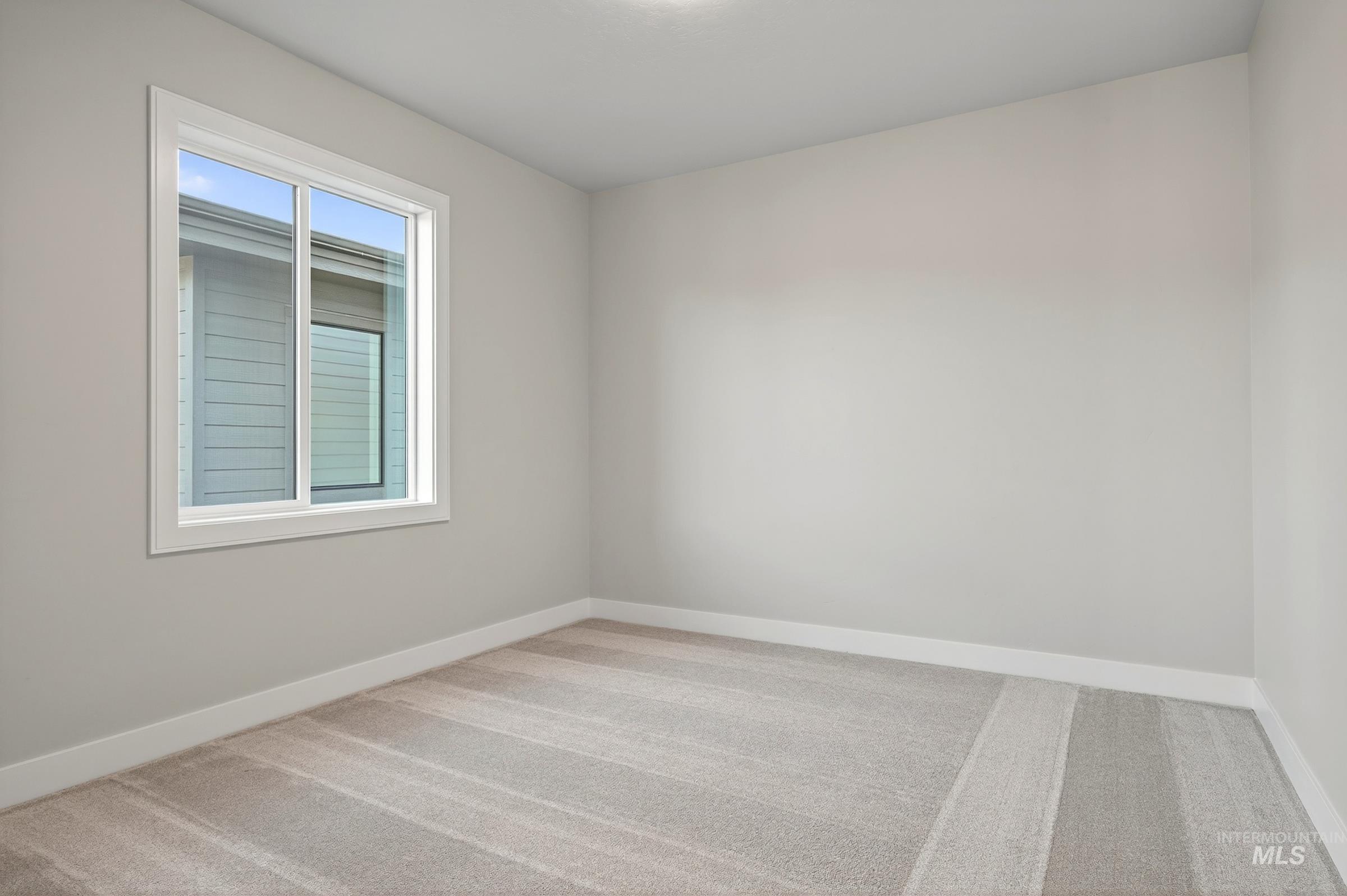 Empty room with light colored carpet and baseboards