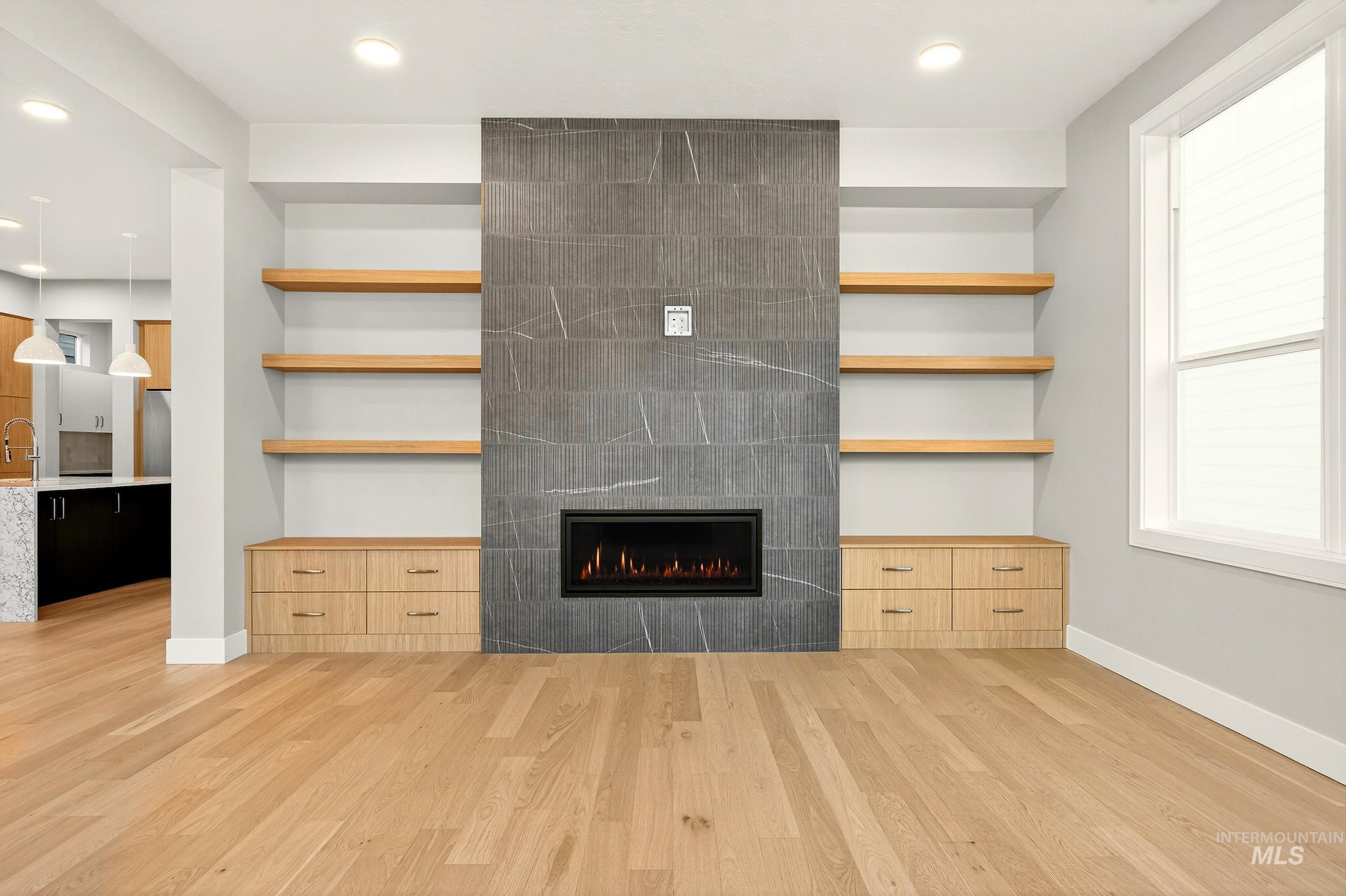 Unfurnished living room featuring recessed lighting, light wood-style flooring, a tiled fireplace, and built in features