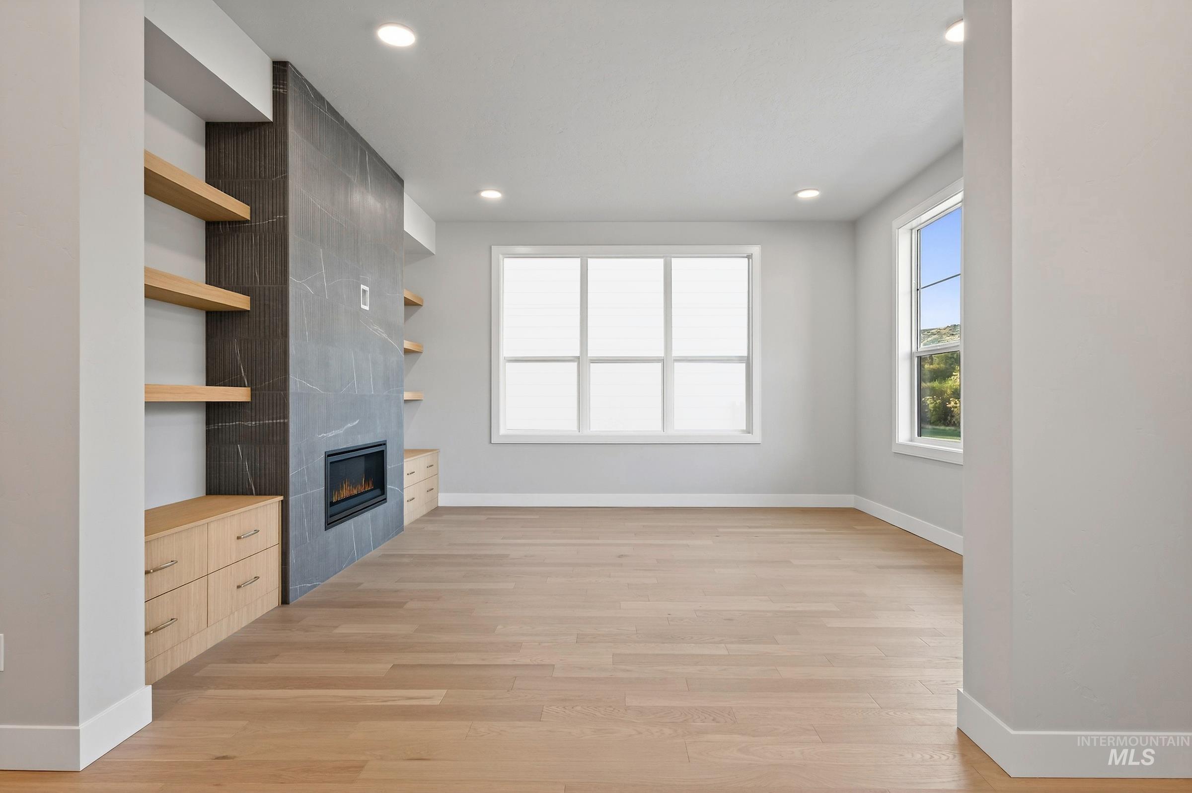 Unfurnished living room with light wood finished floors, a tile fireplace, and recessed lighting