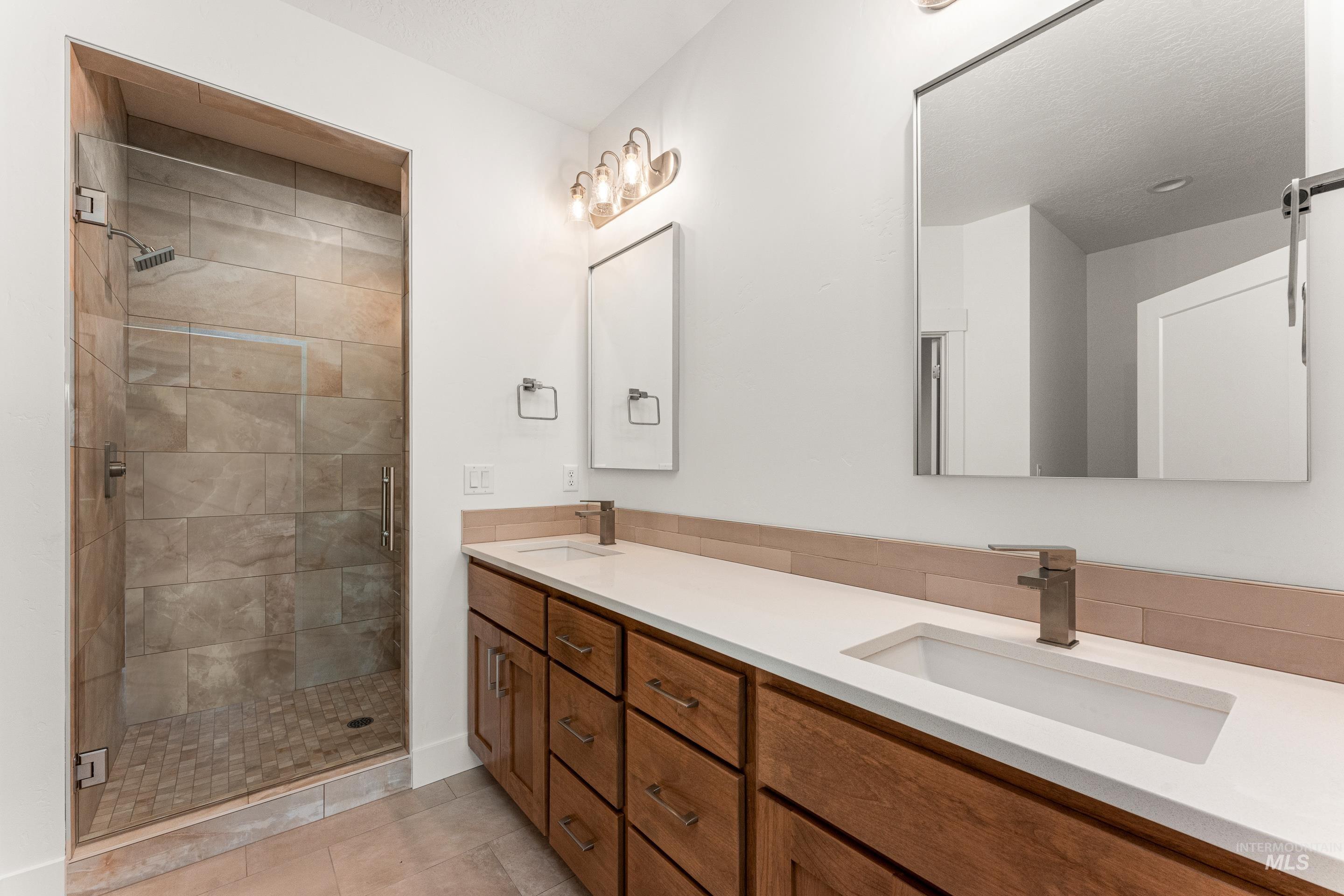 Bathroom with a stall shower, double vanity, and light tile patterned floors