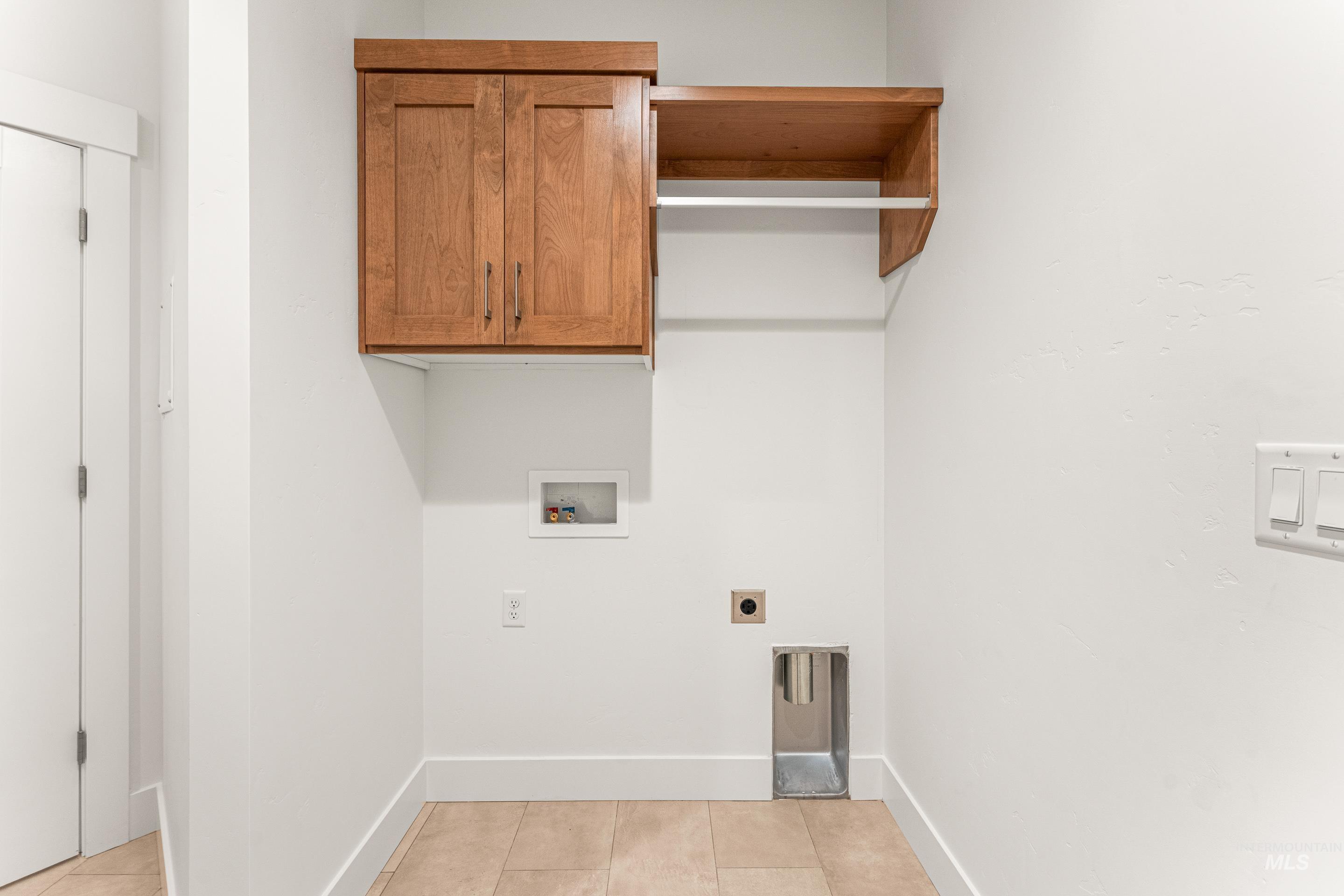 Laundry room with light tile patterned floors, washer hookup, hookup for an electric dryer, and cabinet space
