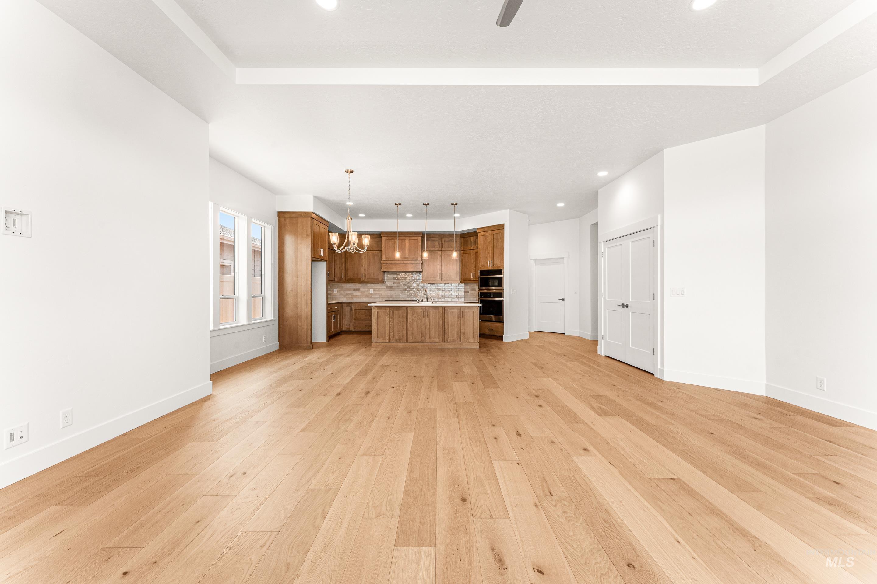 Unfurnished living room with a chandelier, light wood-type flooring, recessed lighting, and ceiling fan