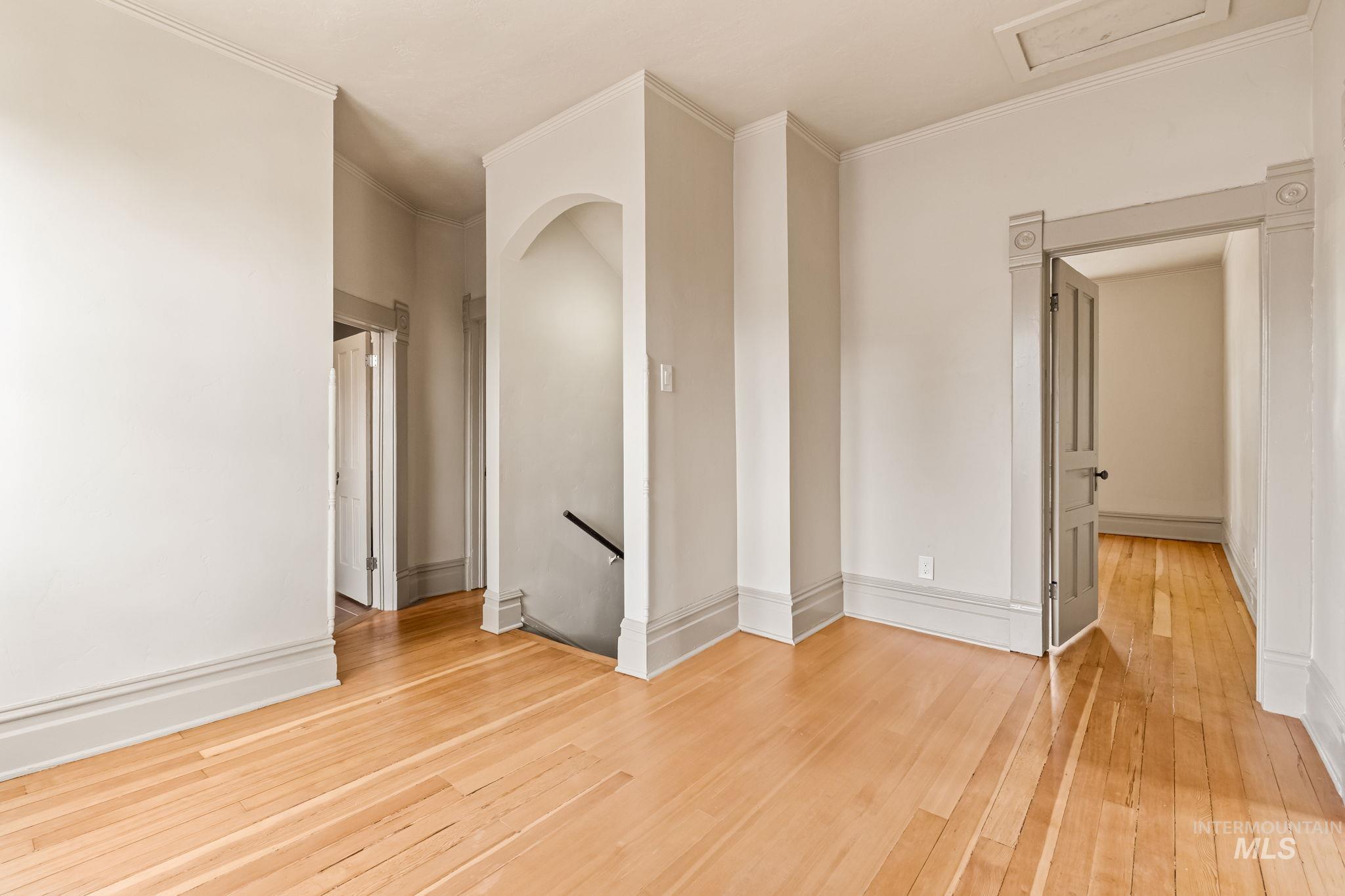 Hardwood flooring throughout featuring an arched doorway and a paneled door with decorative trim