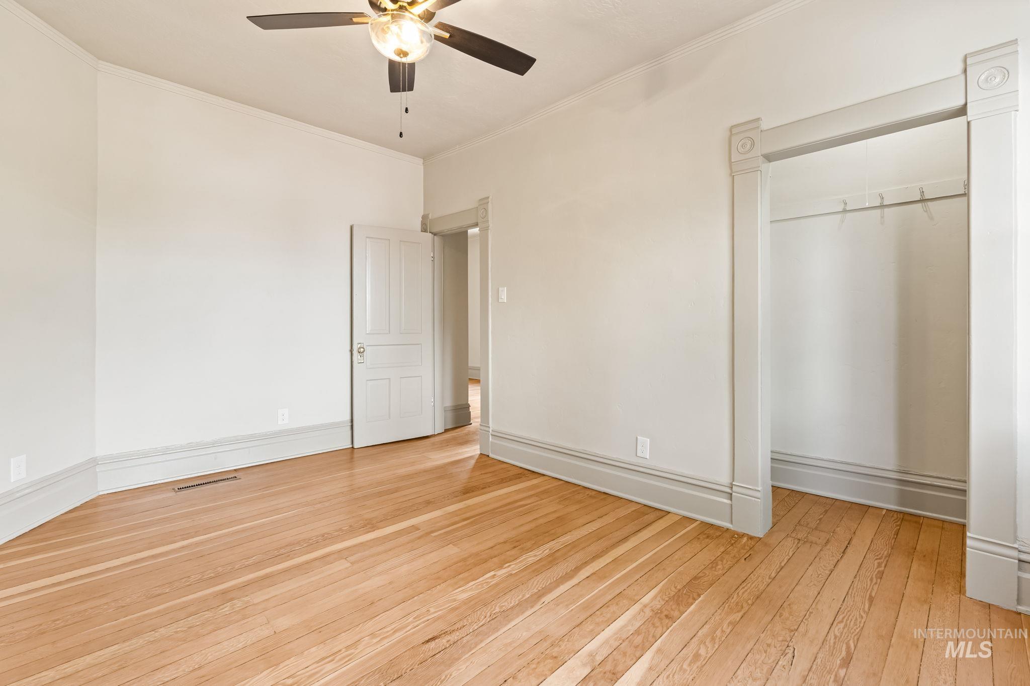 Hardwood flooring extending throughout, complemented by a ceiling fan with integrated lighting