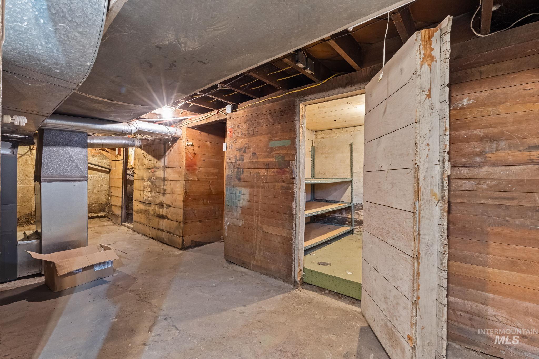 Unfinished basement with concrete flooring and exposed wooden plank walls