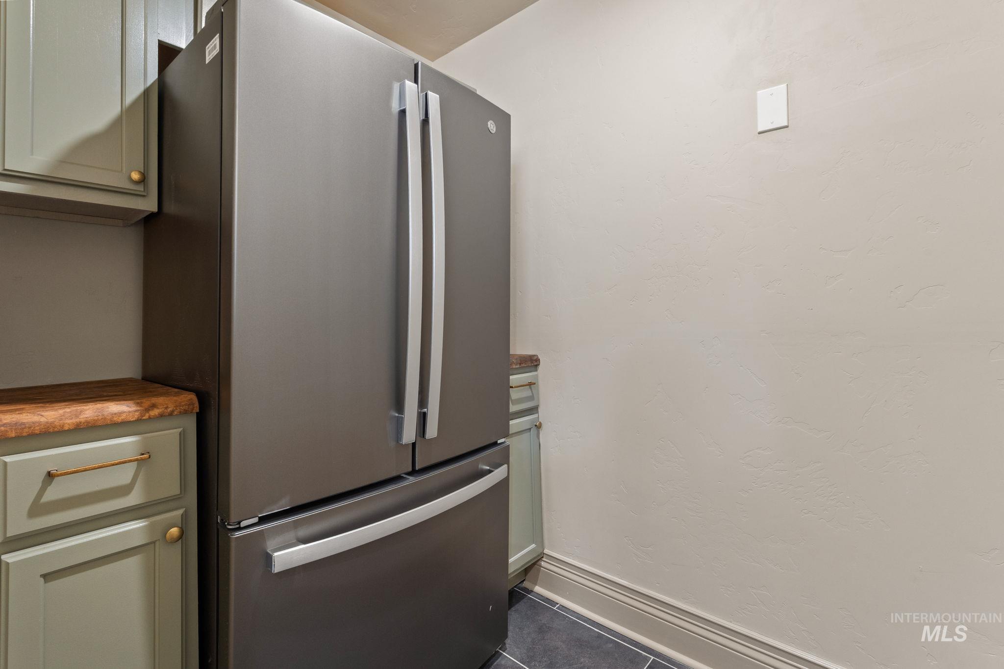 Stainless steel French door refrigerator set against a textured wall
