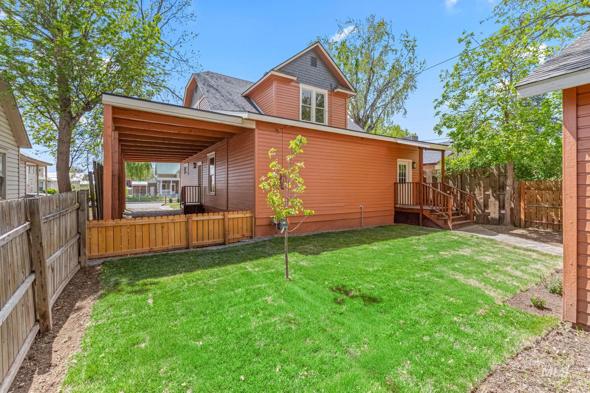 Expansive green lawn with a young tree, bordered by a wooden fence