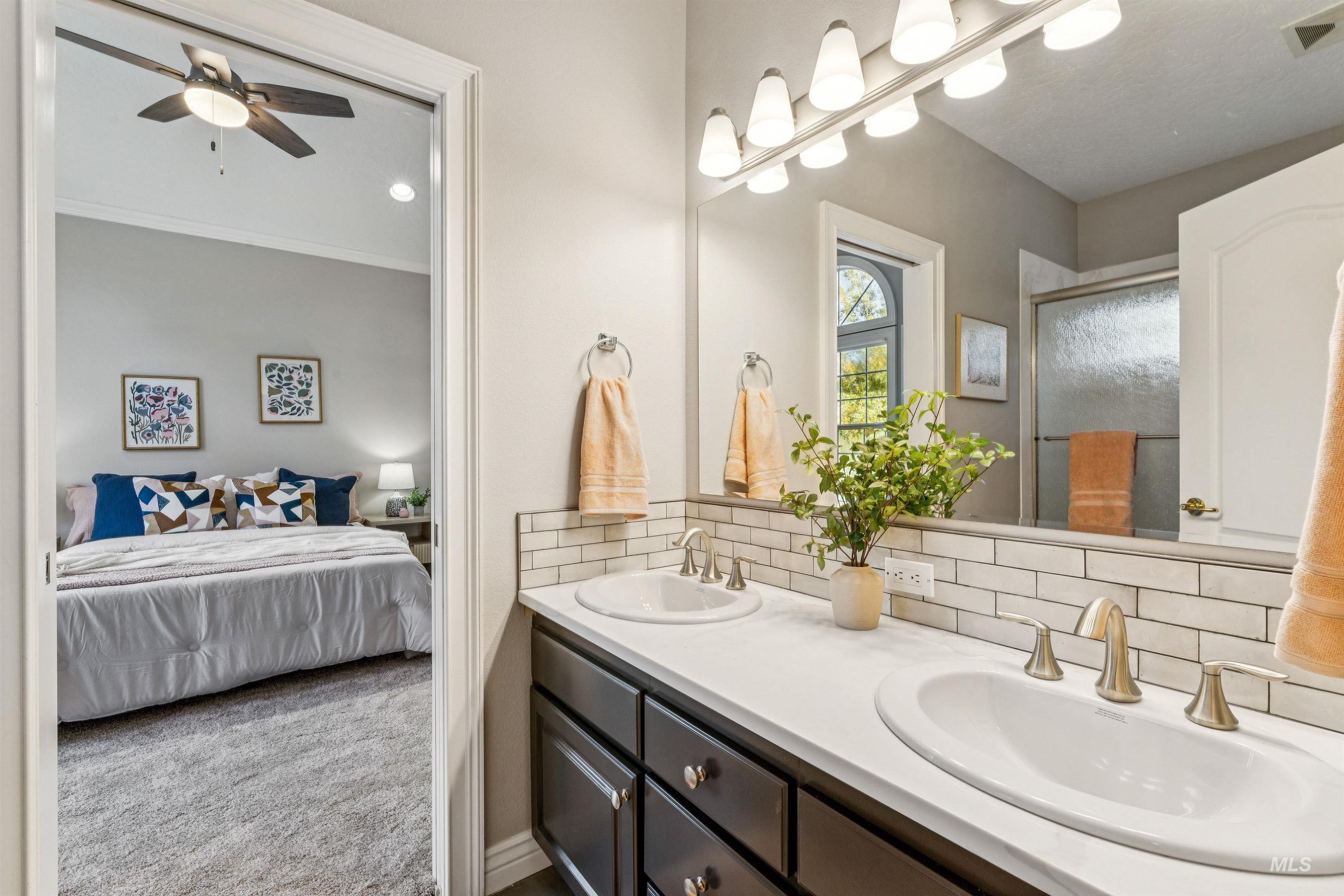 Bathroom featuring ensuite bath, double vanity, a shower stall, decorative backsplash, and light colored carpet