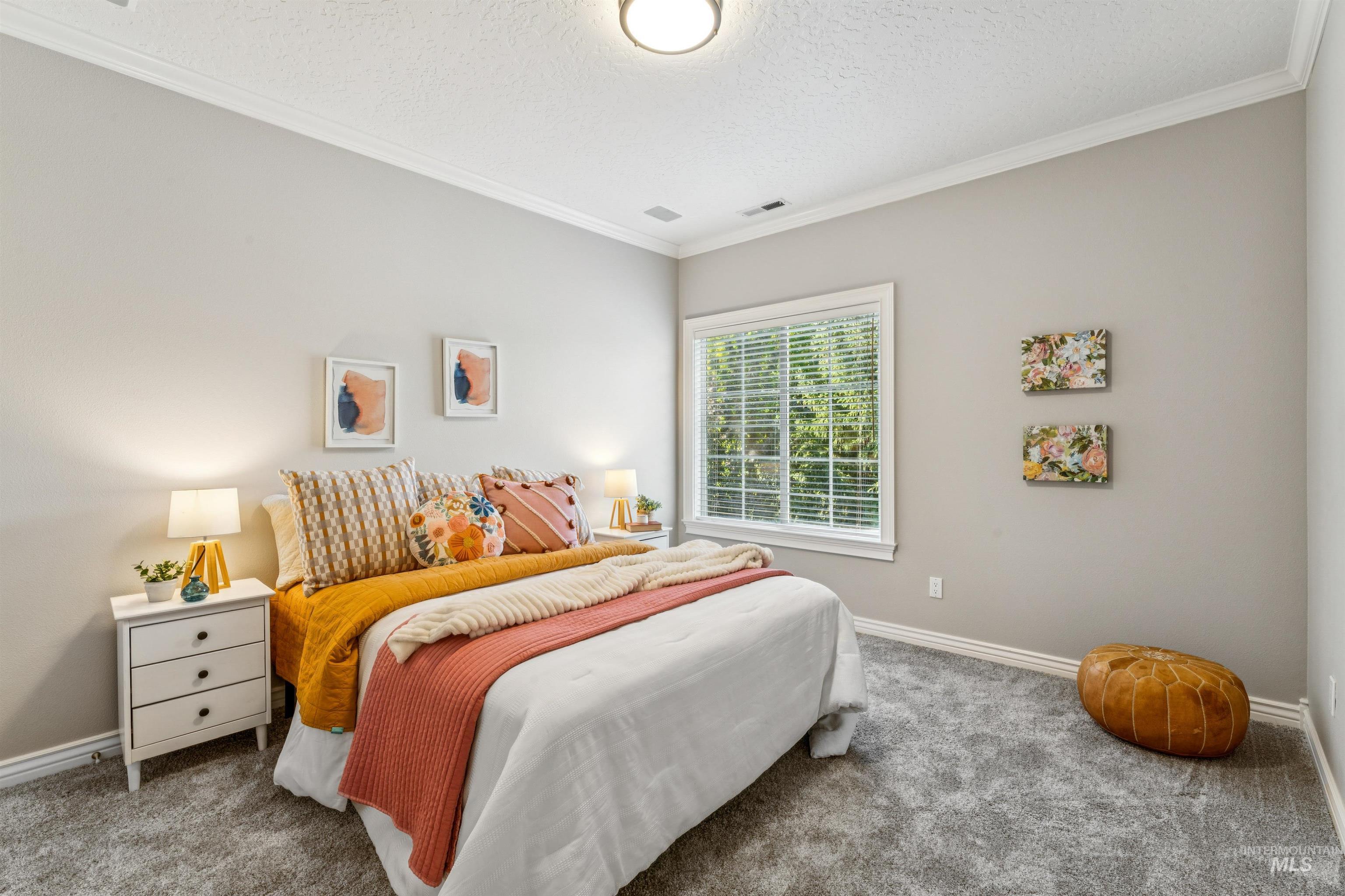 Carpeted bedroom featuring ornamental molding and a textured ceiling