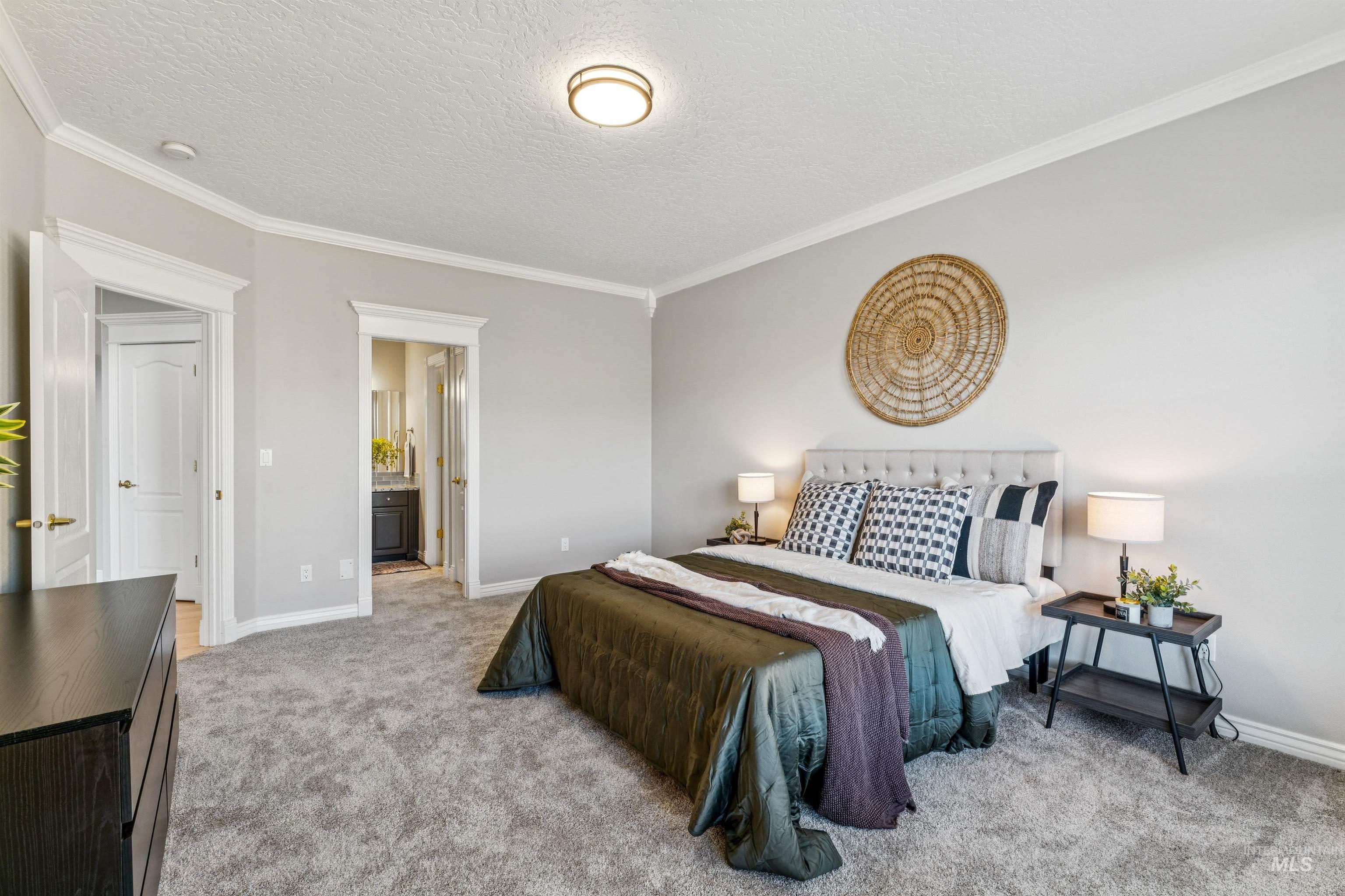 Bedroom with crown molding, light colored carpet, ensuite bath, and a textured ceiling