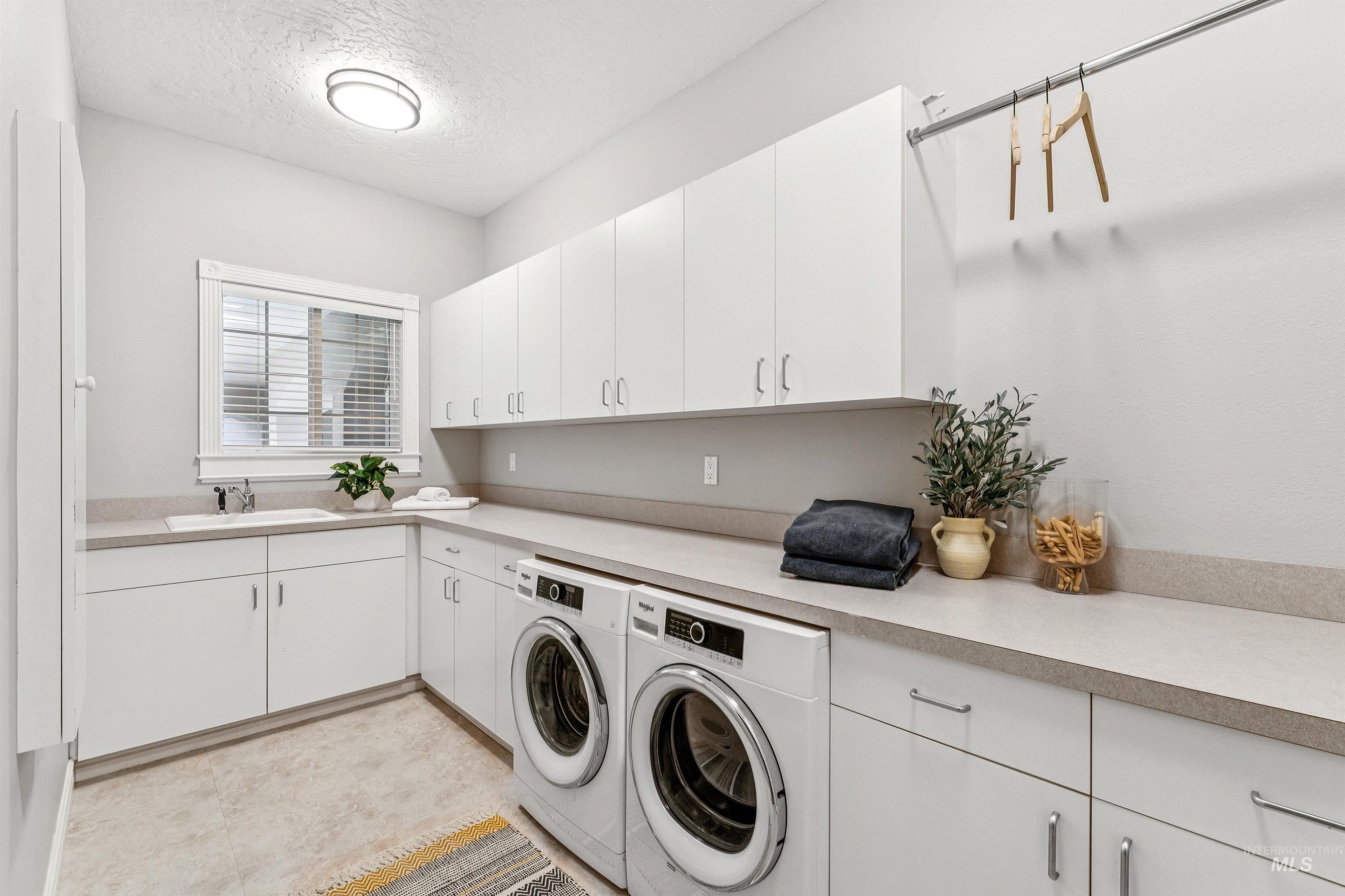 Washroom featuring cabinet space, a textured ceiling, and independent washer and dryer