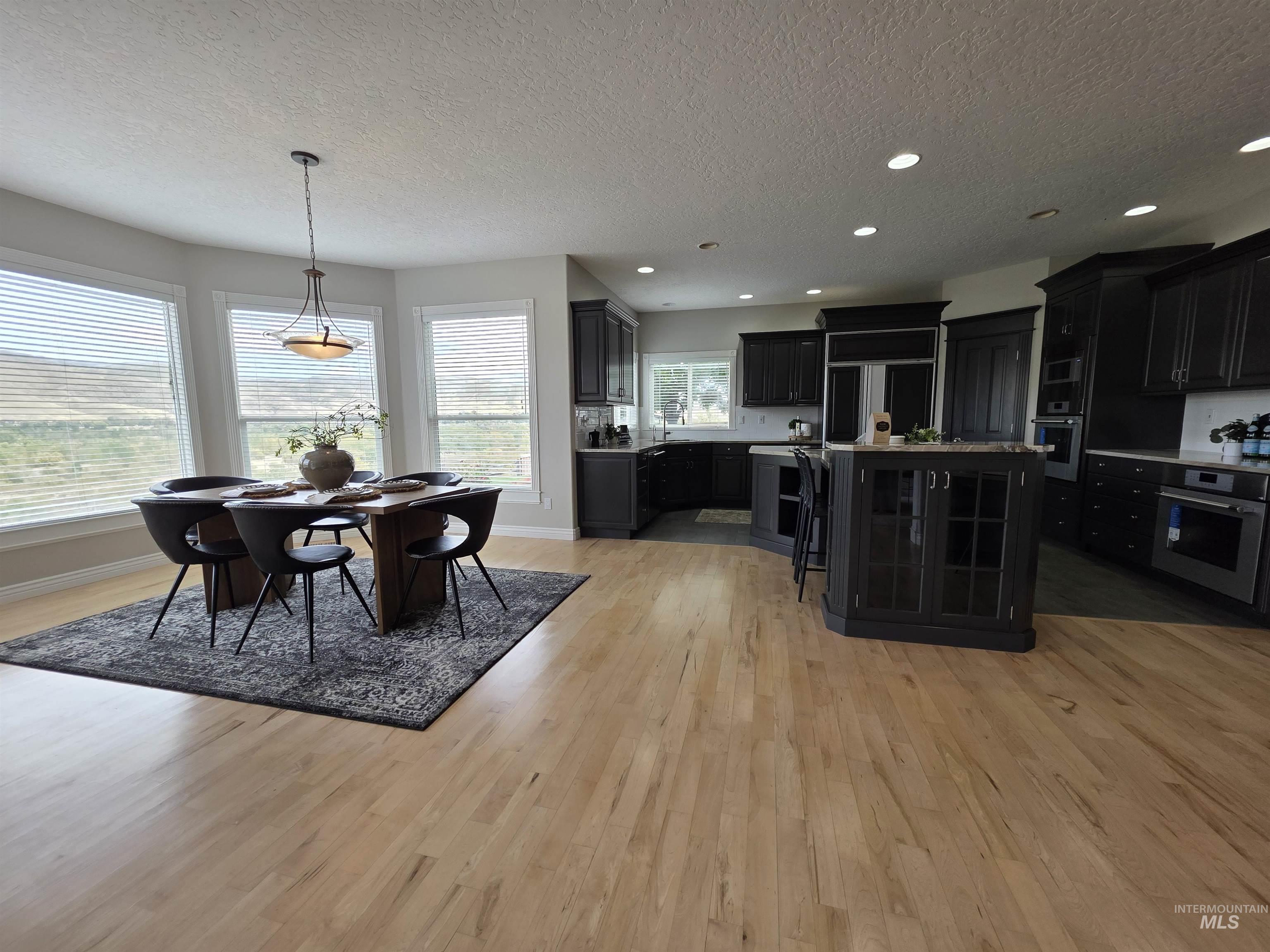 Kitchen featuring a textured ceiling, dark cabinets, oven, paneled refrigerator, and decorative light fixtures