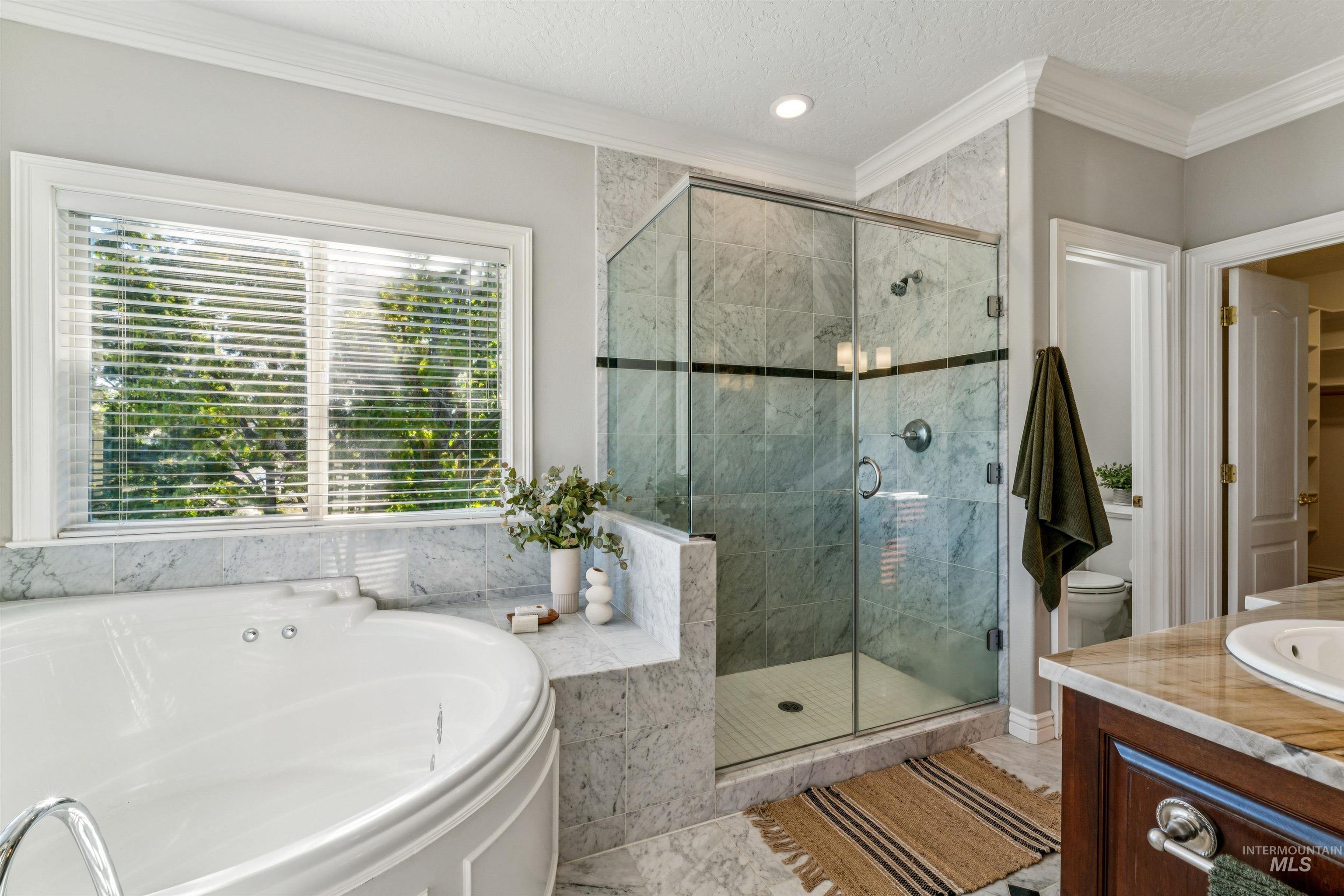 Bathroom with crown molding, a stall shower, a textured ceiling, a bath, and vanity