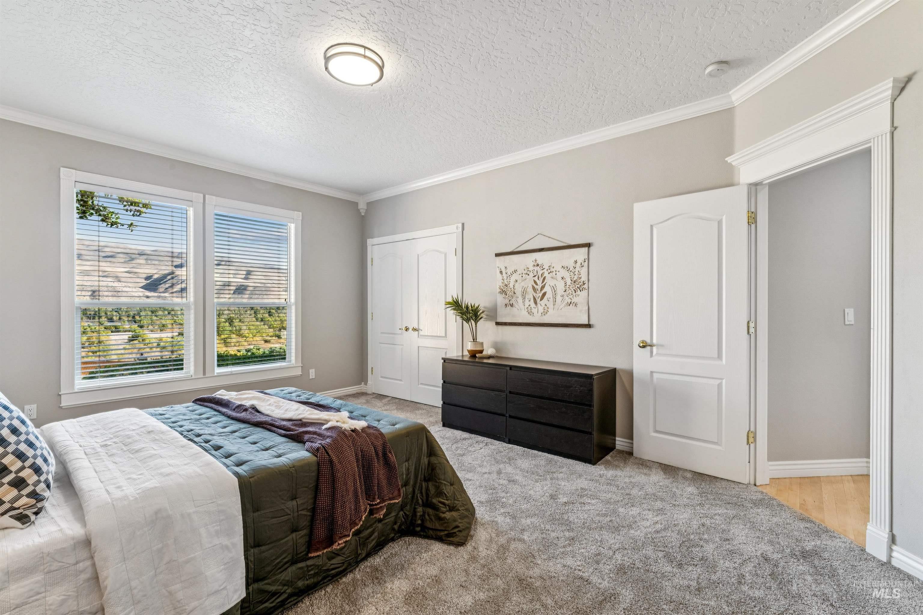 Bedroom featuring ornamental molding, carpet, a textured ceiling, and a closet