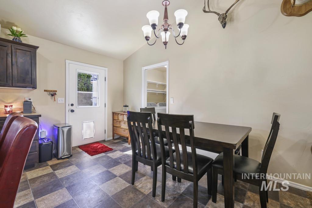 Dining area with vaulted ceiling, a chandelier, and dark stone finish floors