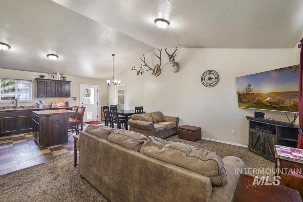 Living room featuring dark carpet, vaulted ceiling, and a chandelier