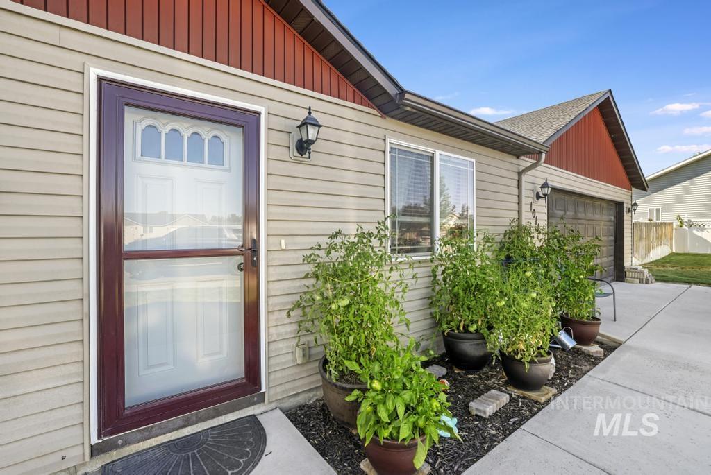 Doorway to property with an attached garage, concrete driveway, and board and batten siding