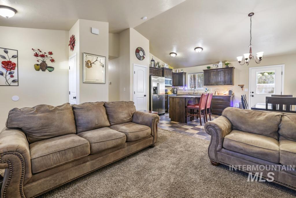 Carpeted living room featuring lofted ceiling and a chandelier