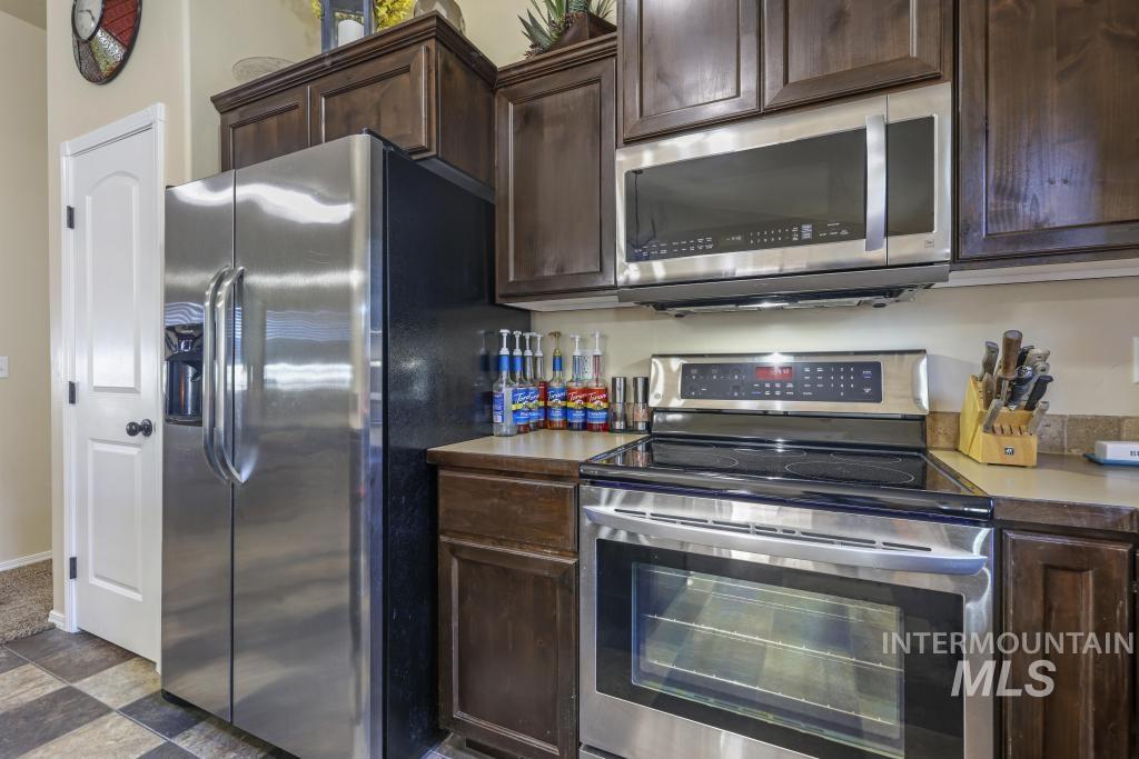 Kitchen with stainless steel appliances, dark brown cabinets, and light countertops