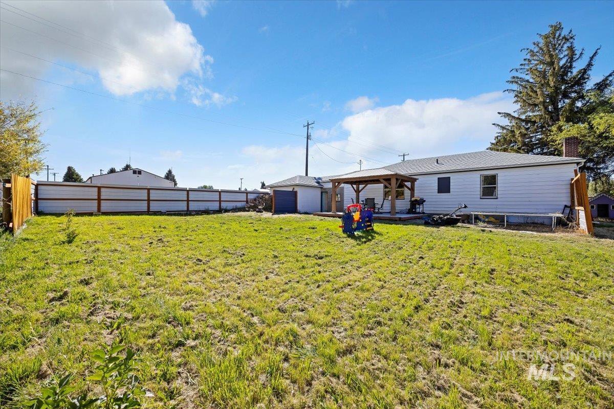 Back of house with a gazebo, a fenced backyard, and an outdoor structure