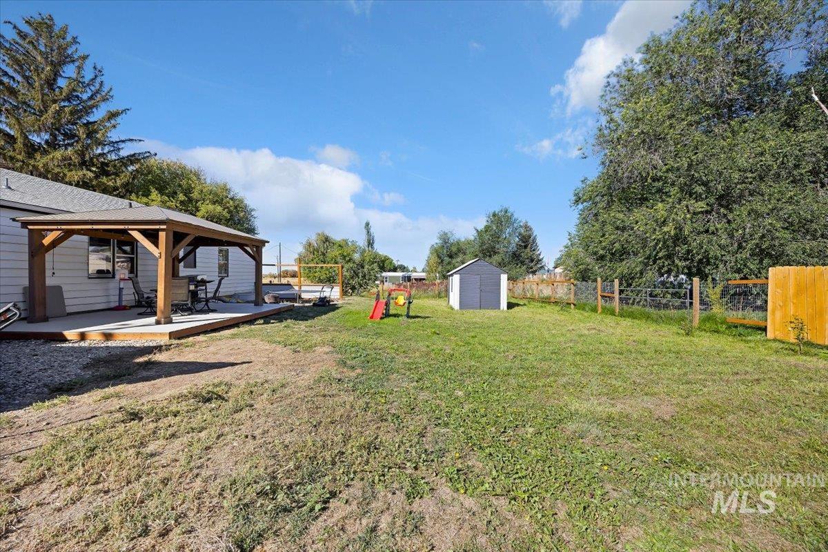 Fenced backyard with a shed, a gazebo, and a playground