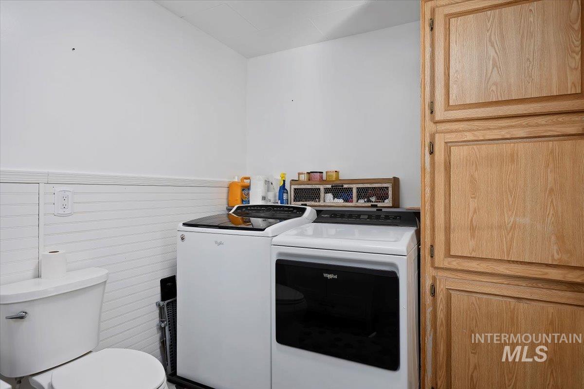 Washroom with separate washer and dryer and a wainscoted wall