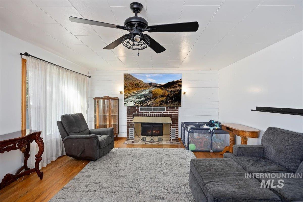 Living area with a fireplace, wood finished floors, and a ceiling fan