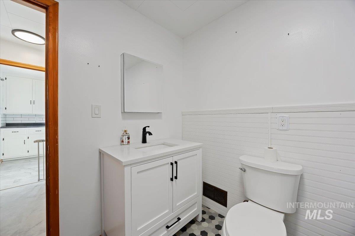 Half bath featuring vanity, tasteful backsplash, and wainscoting